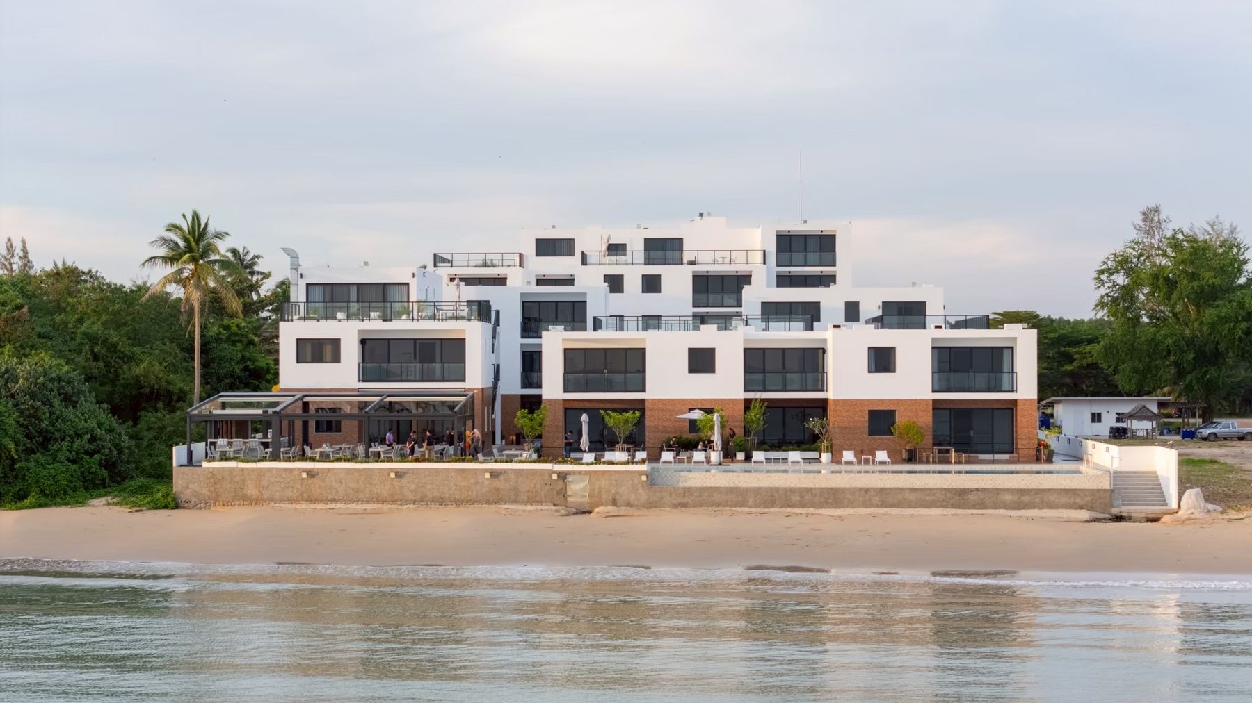 The Village Chumphon seen from the beach, with the pool and restaurant at the water's edge