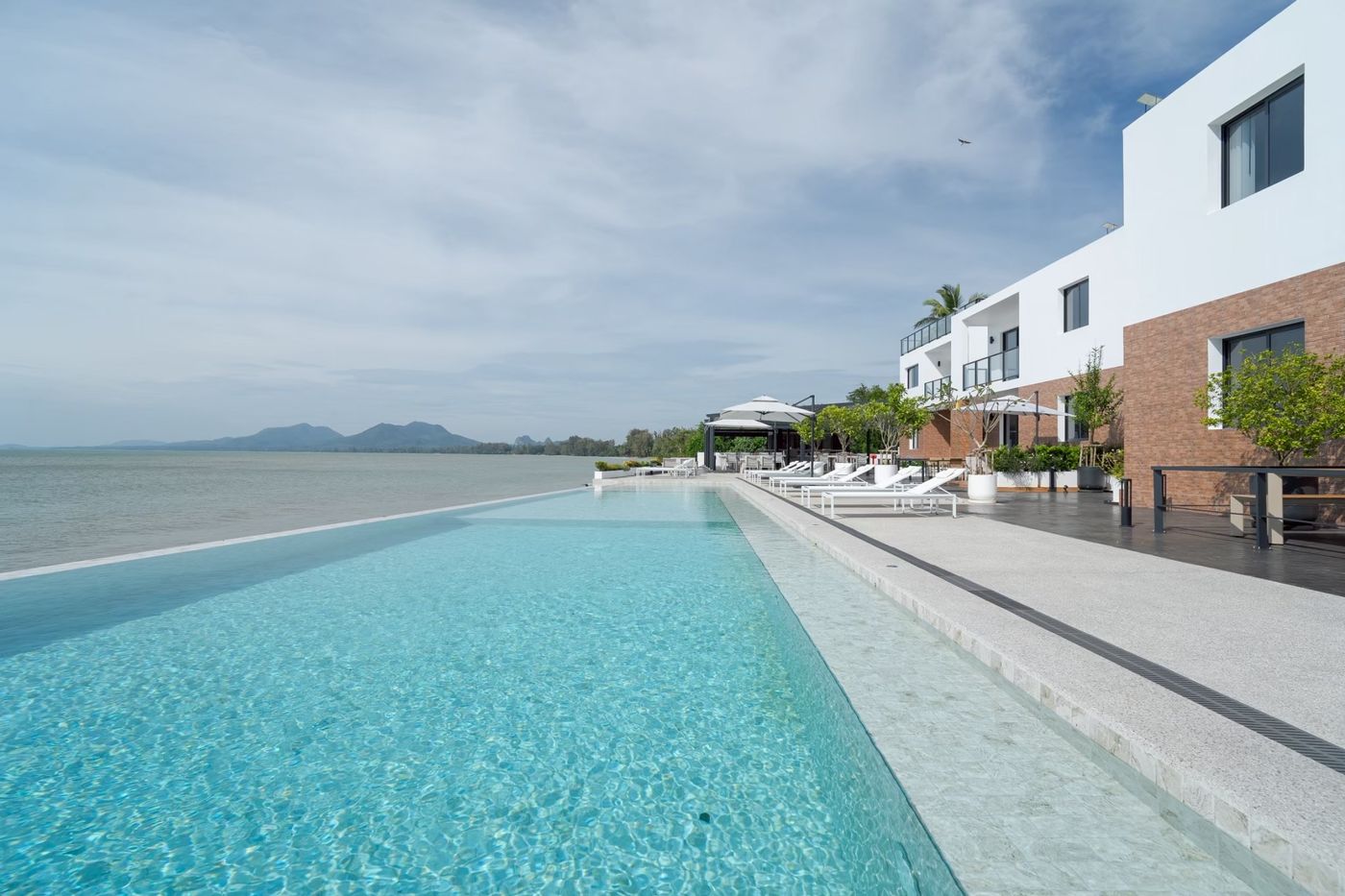 Infinity pool beside the sea, with mountains along the bay