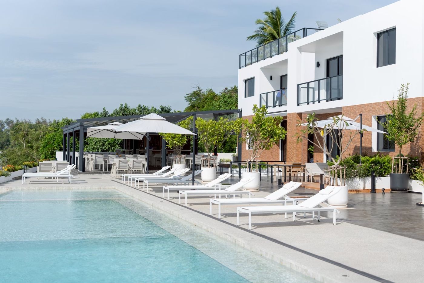 Pool deck with sun loungers and the beachfront restaurant
